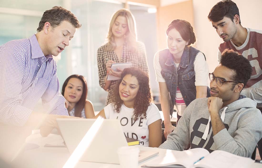 College students and a professor collaborating in an open innovation center with technology