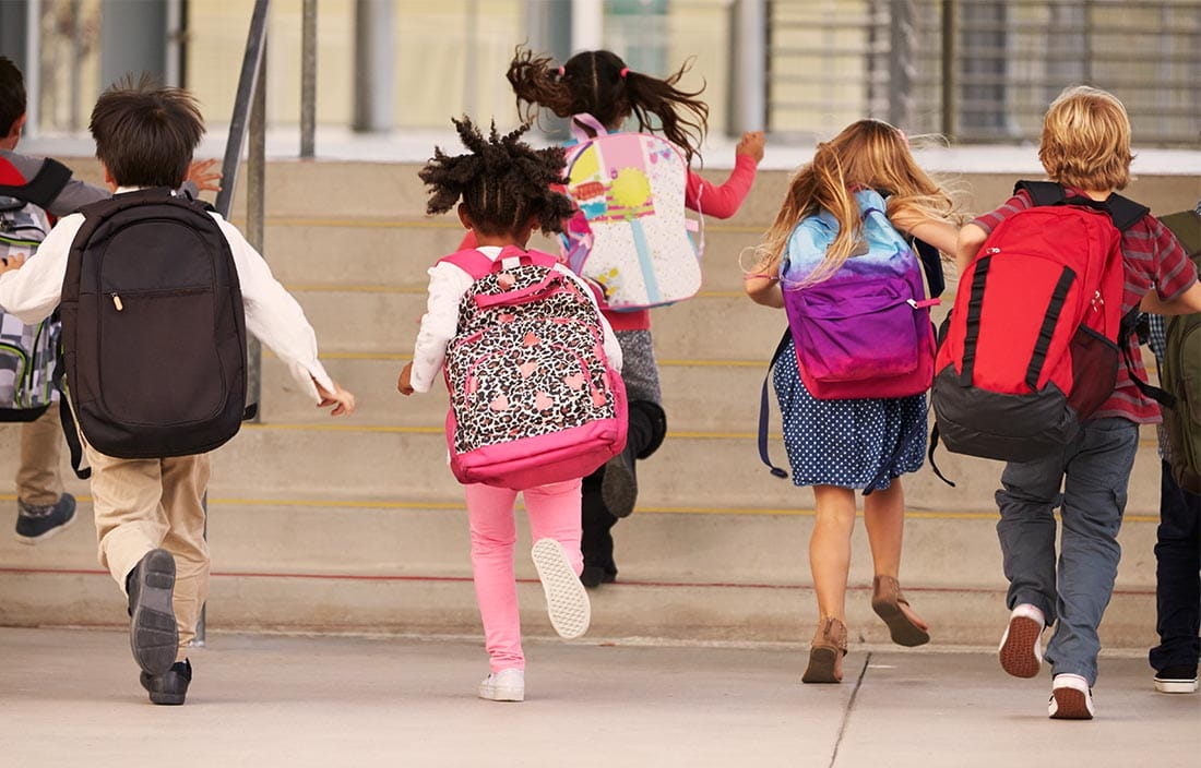 Elementary students running into a K12 school building