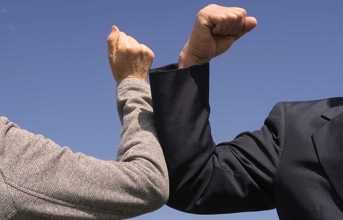 Two seniors 'high-fiving' with their arms to avoid hand contact because of COVID