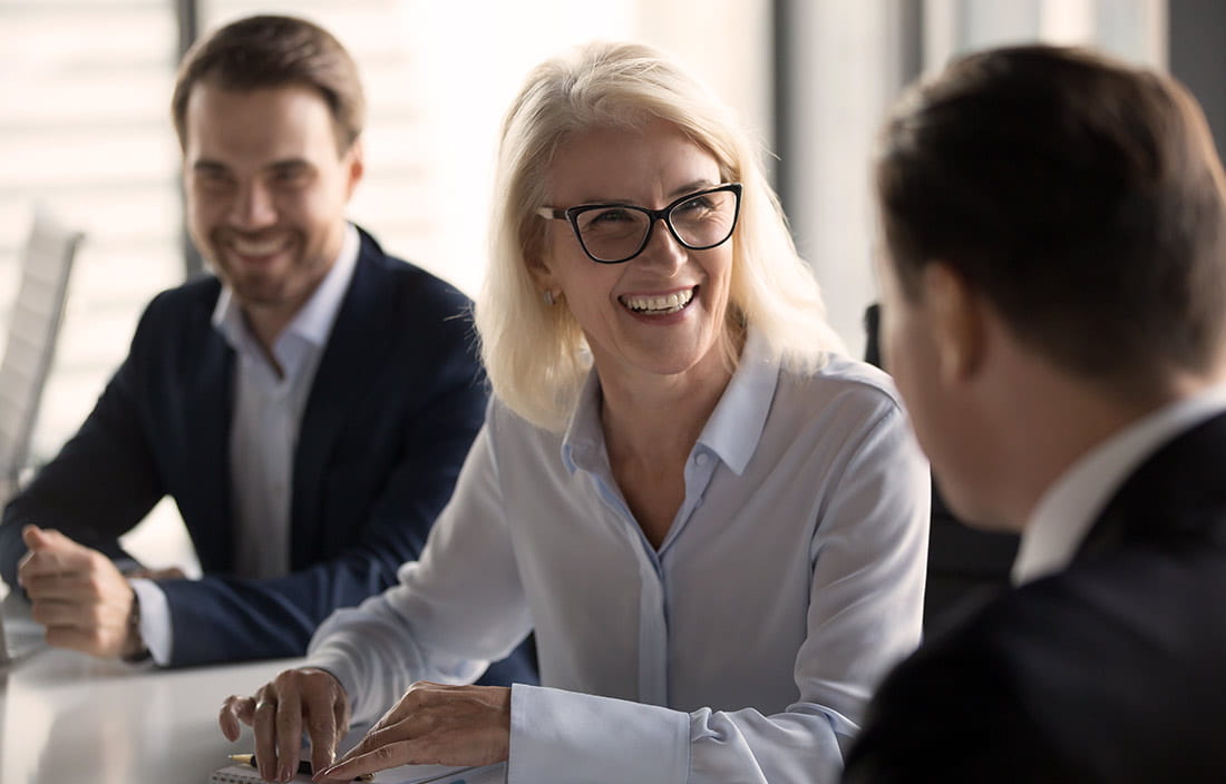 Photo of 2 men and a women at a conference table, laughing and talking about fundamentals of goverance for senior living organizations