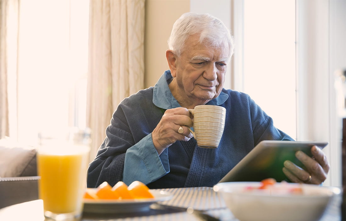 Image of older man drinking coffee and reading a newspaper
