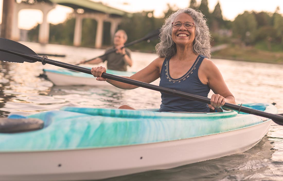 Younger older adult seniors kayaking in a river living an active adult lifestyle