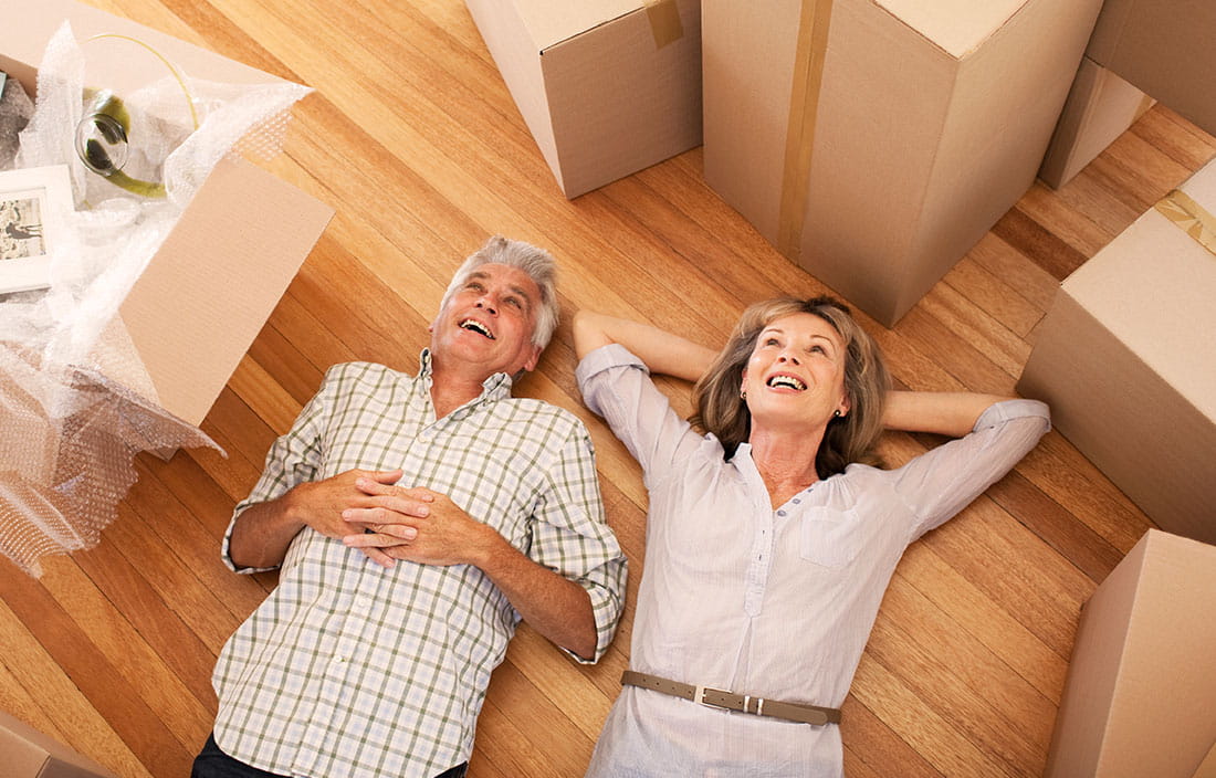 Happy baby boomer couple lying on the floor of their new home in an active adult community