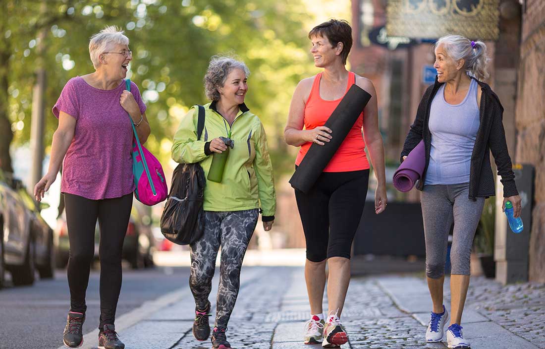 Older adults talking and walking down a street in fitness clothes to their active adult home