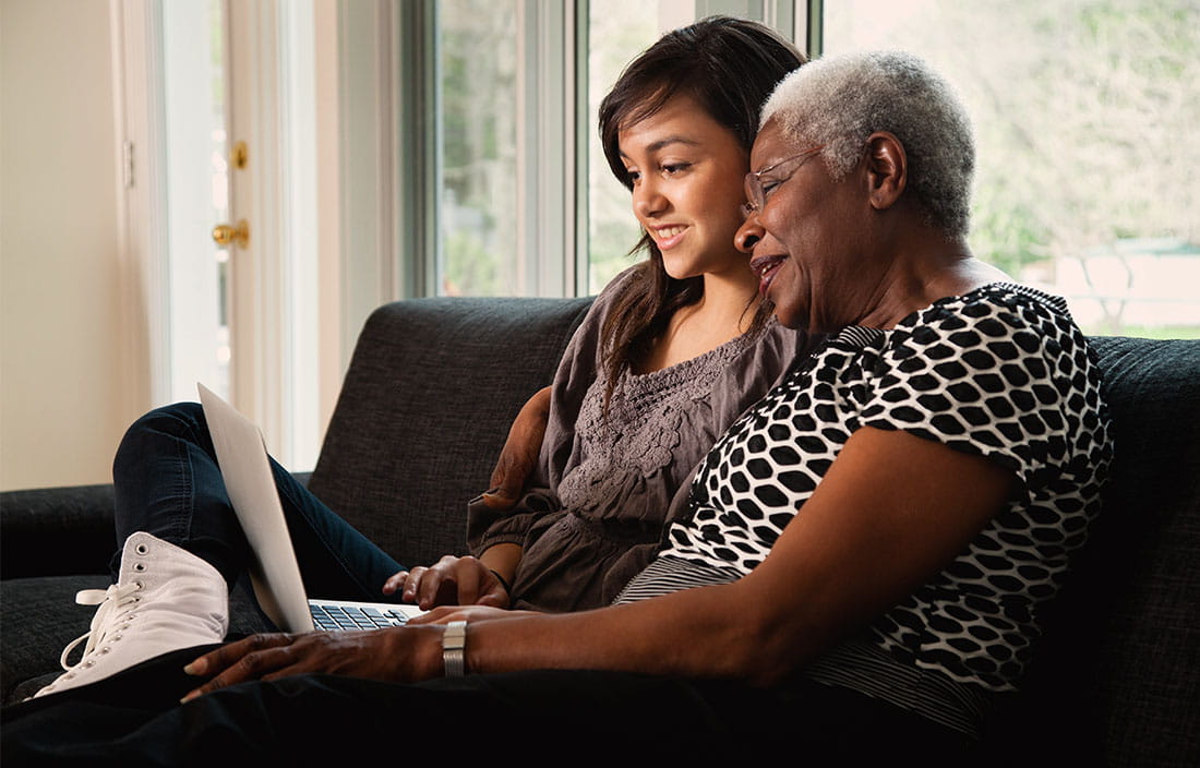 Senior woman and young girl looking at a computer while sitting on a couch