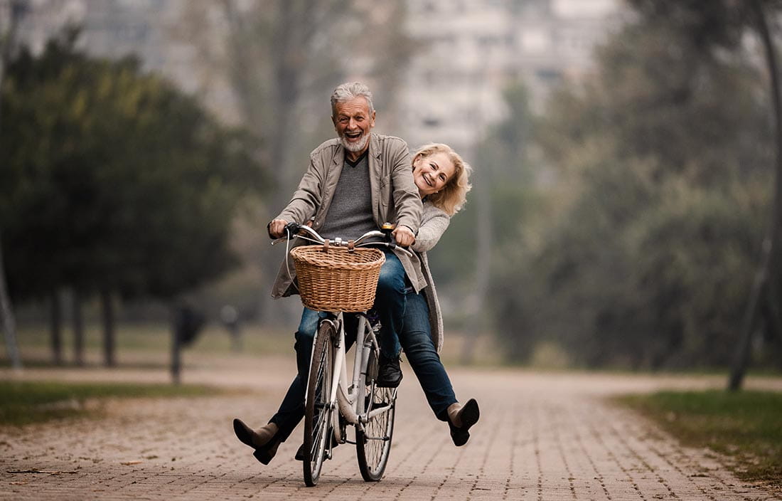 Happy mature couple having fun on a bicycle in autumn day
