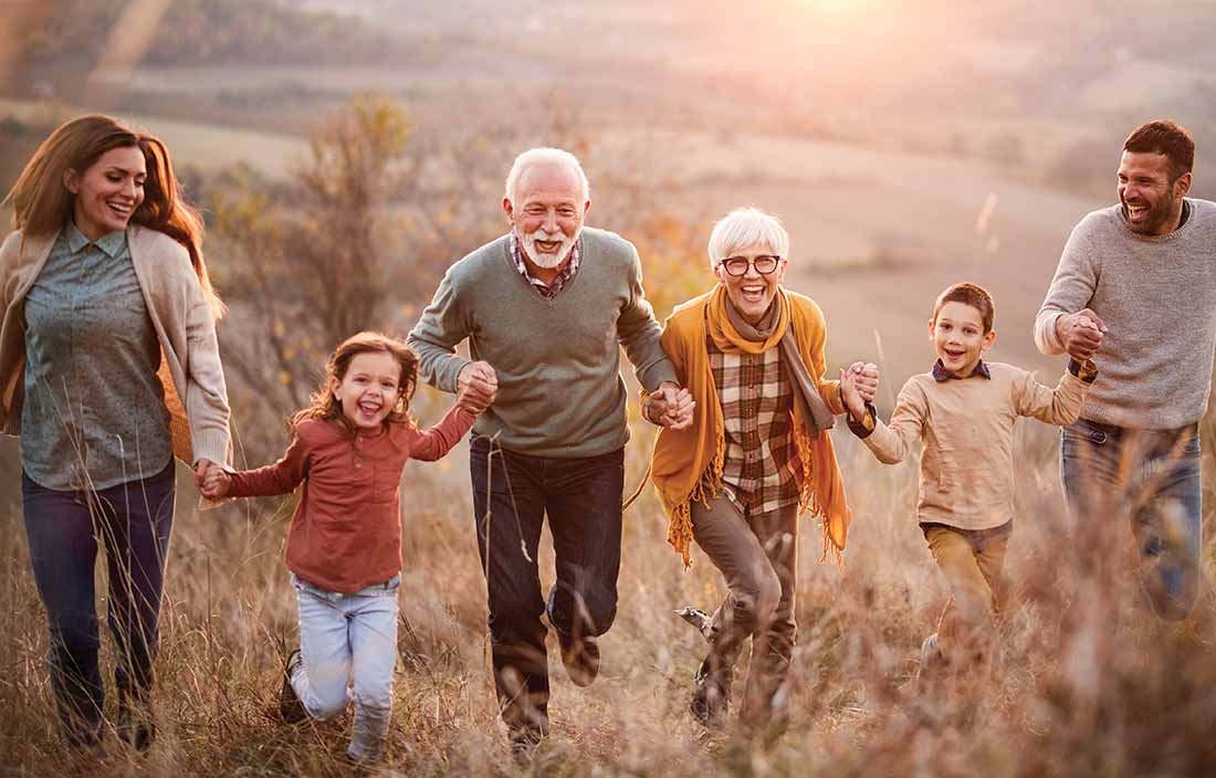 A family running through a field together holding hands.