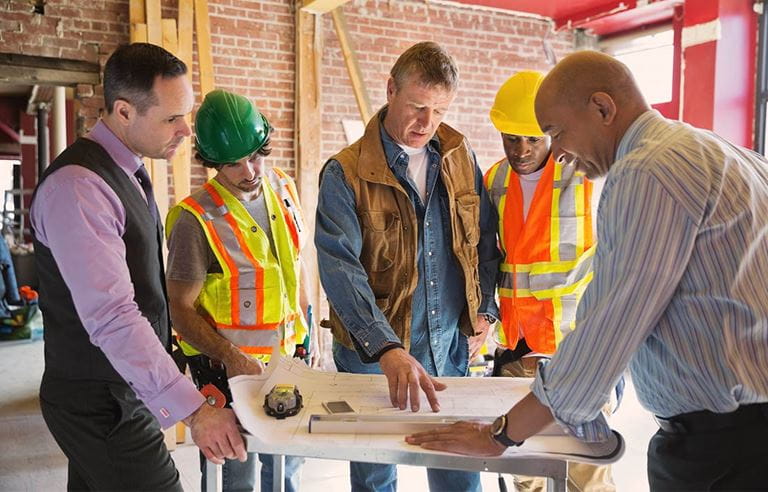Construction site with project team of owner's representative, project manager, construction manager, architect, and contractors