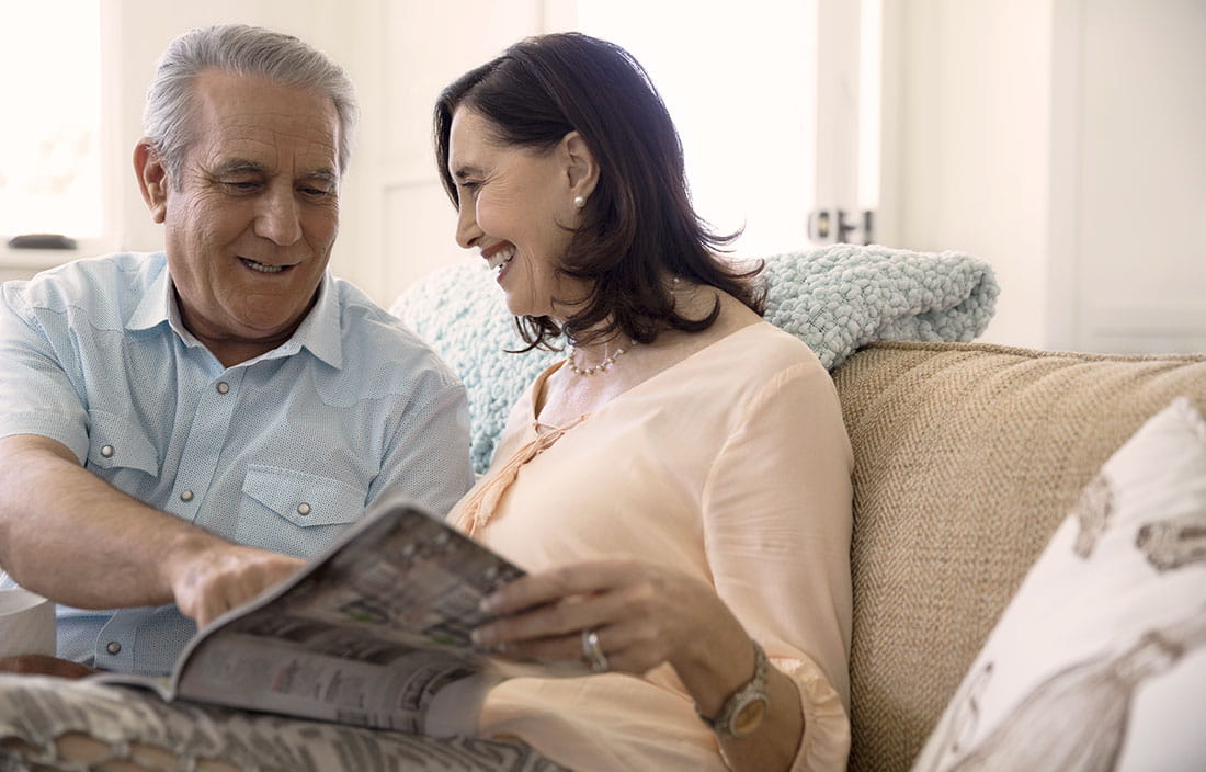 Senior couple sitting on a couch reading a senior housing brochure