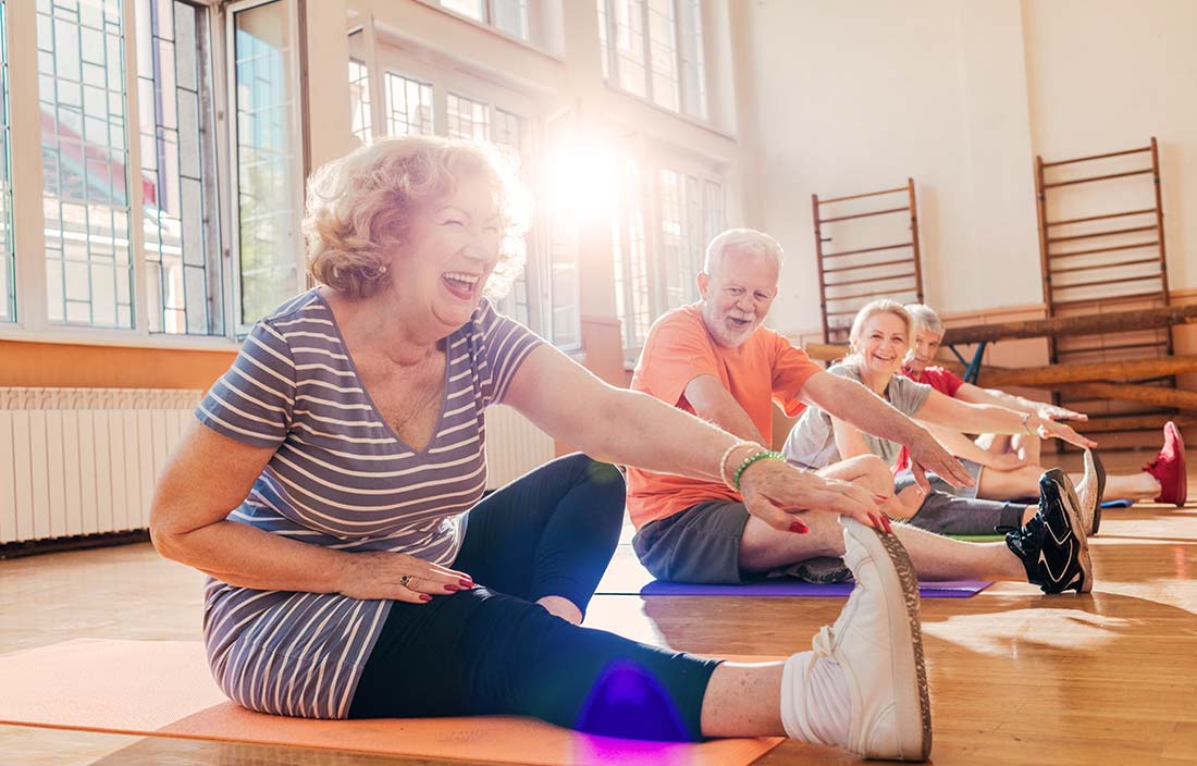 Seniors stretching in a gym during a wellness class at a senior living community