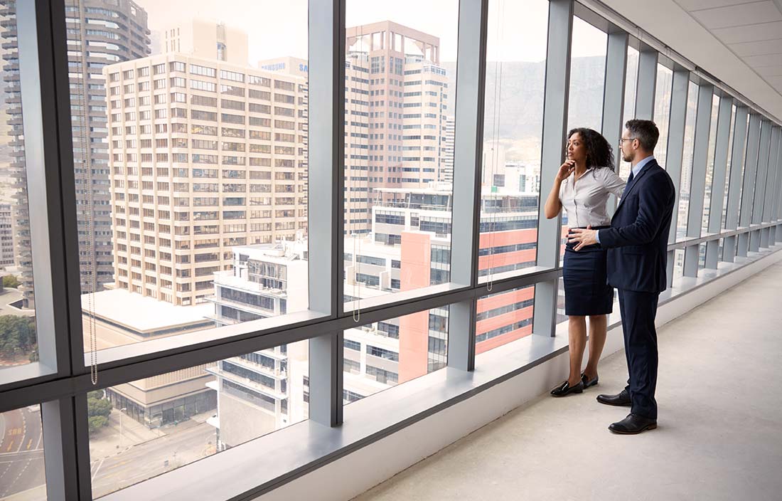 Portrait Of New Business Owners By Empty Office Window