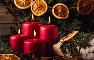 Red candles in an Advent wreath decoration on wooden dark background.