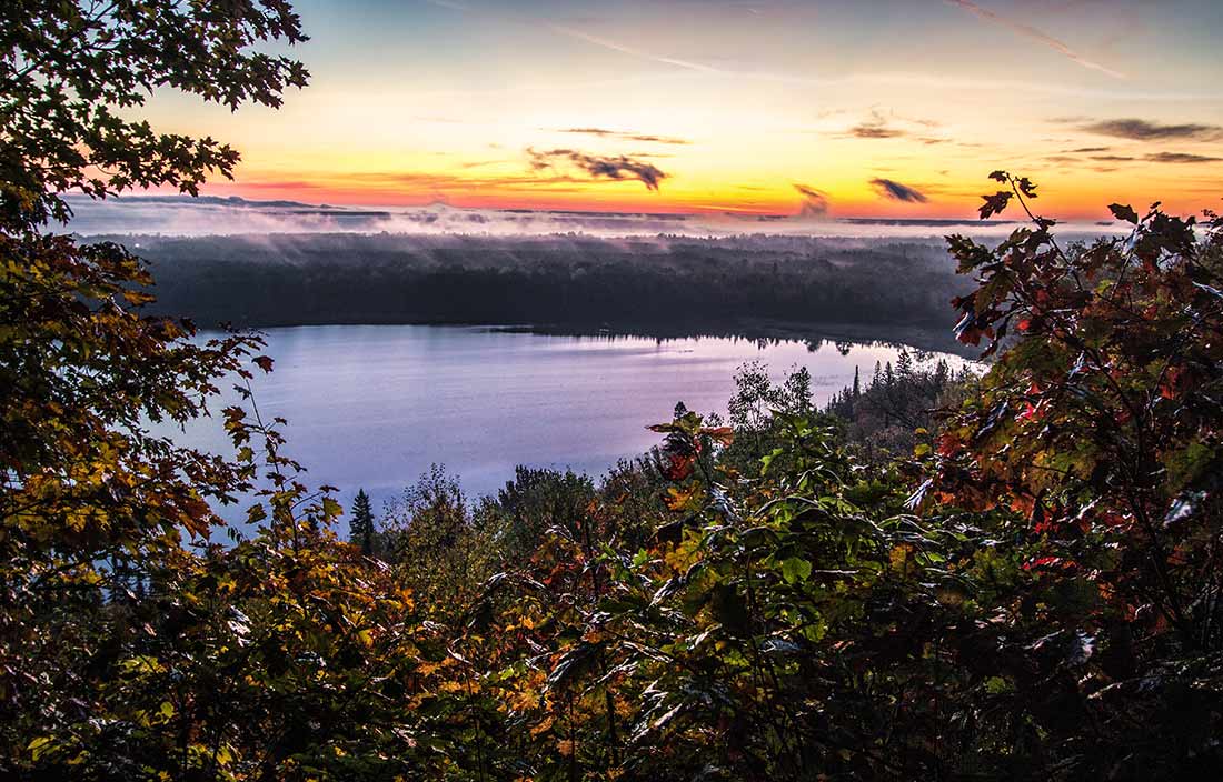 View of a lake at sunset through foliage from an elevation point