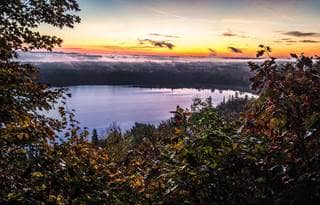 View of a lake at sunset through foliage from an elevation point
