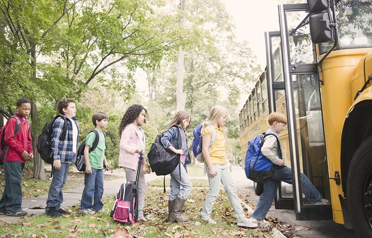 School children entering a school bus in fall