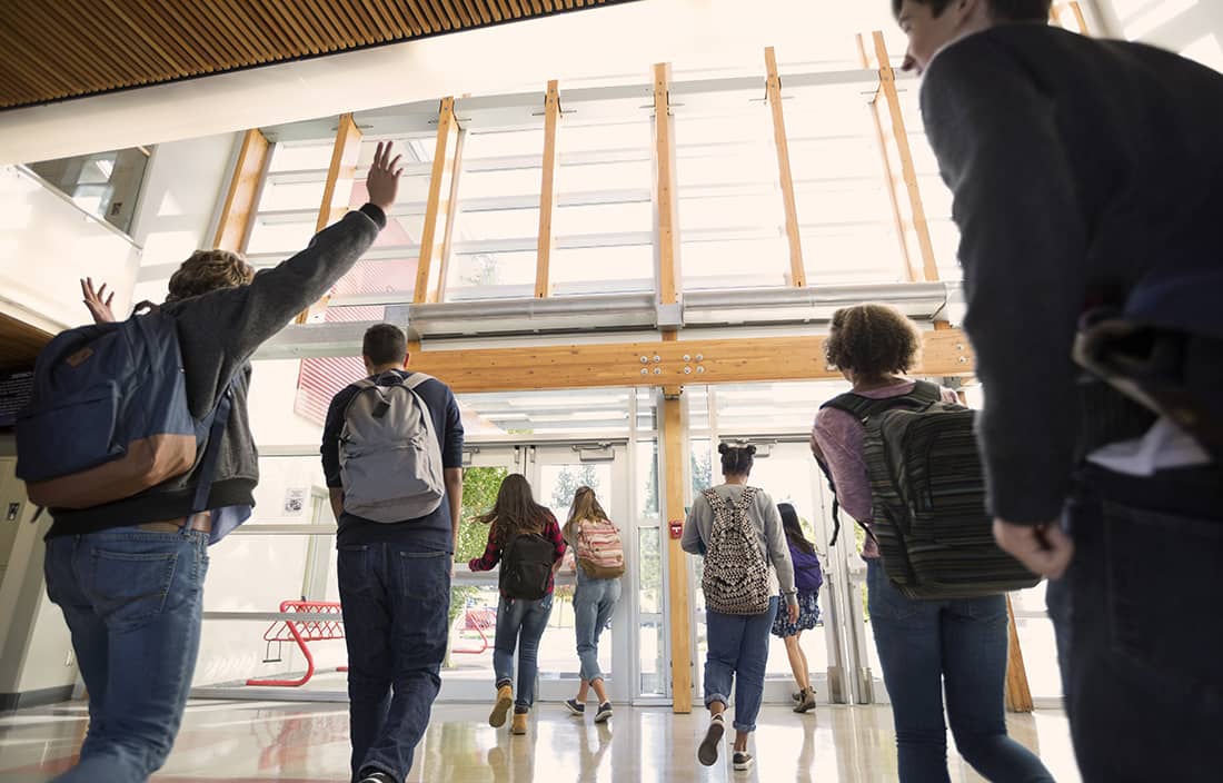 Children leaving a modern school building through doors with ceiling high windows and lots of natural light