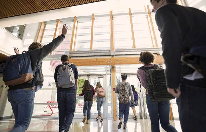 Children leaving a modern school building through doors with ceiling high windows and lots of natural light