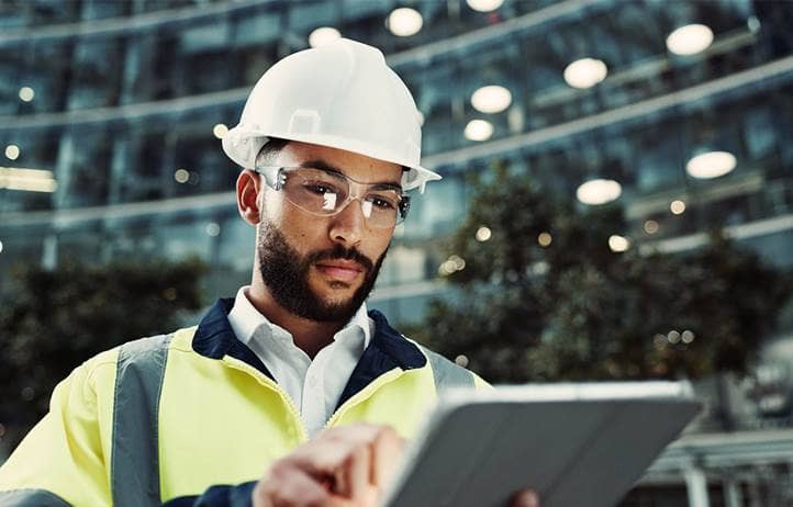 Close up of an industrial worker in a construction helmet looking at a tablet