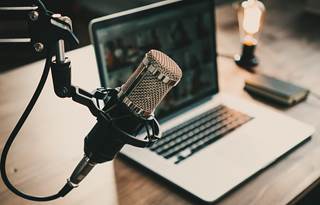 Podcast microphone and laptop on a wood table