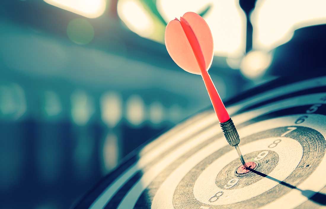 Bullseye or dart board has dart arrow throw hitting the center of a shooting target
