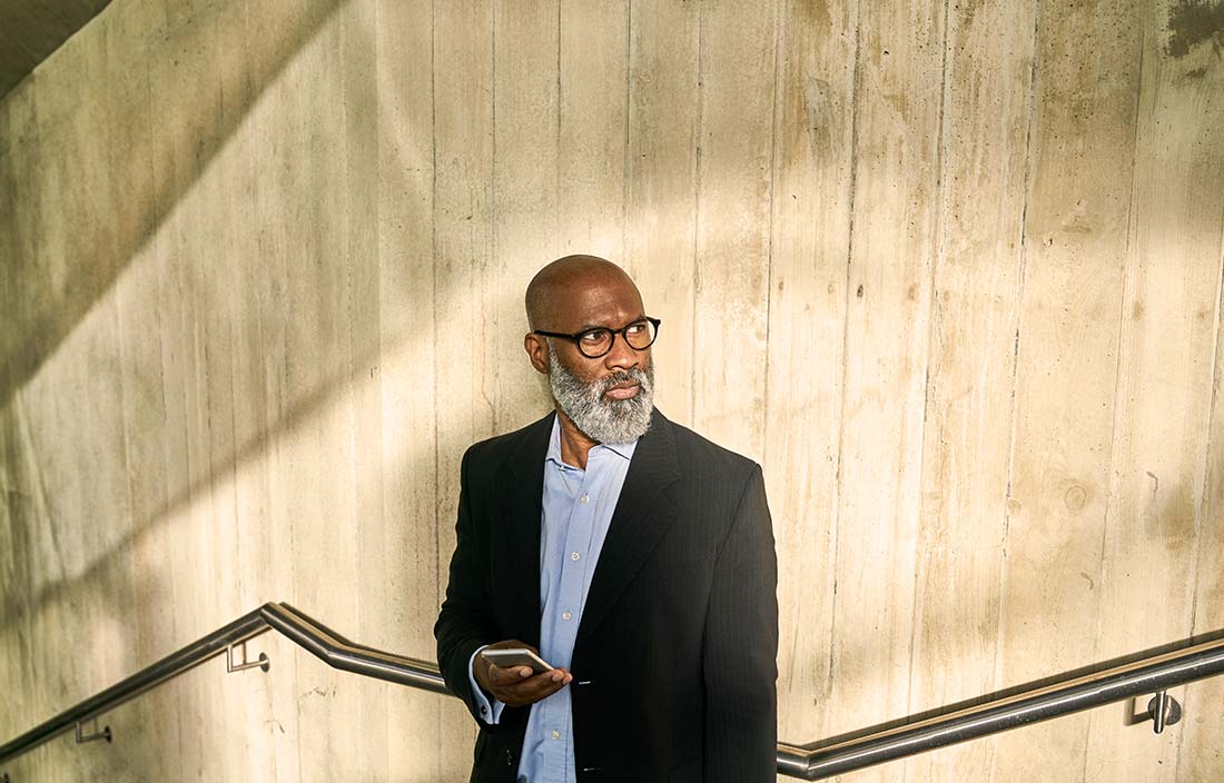 Real estate investor with a beard and glasses in a stairwell, looking slightly over his shoulder