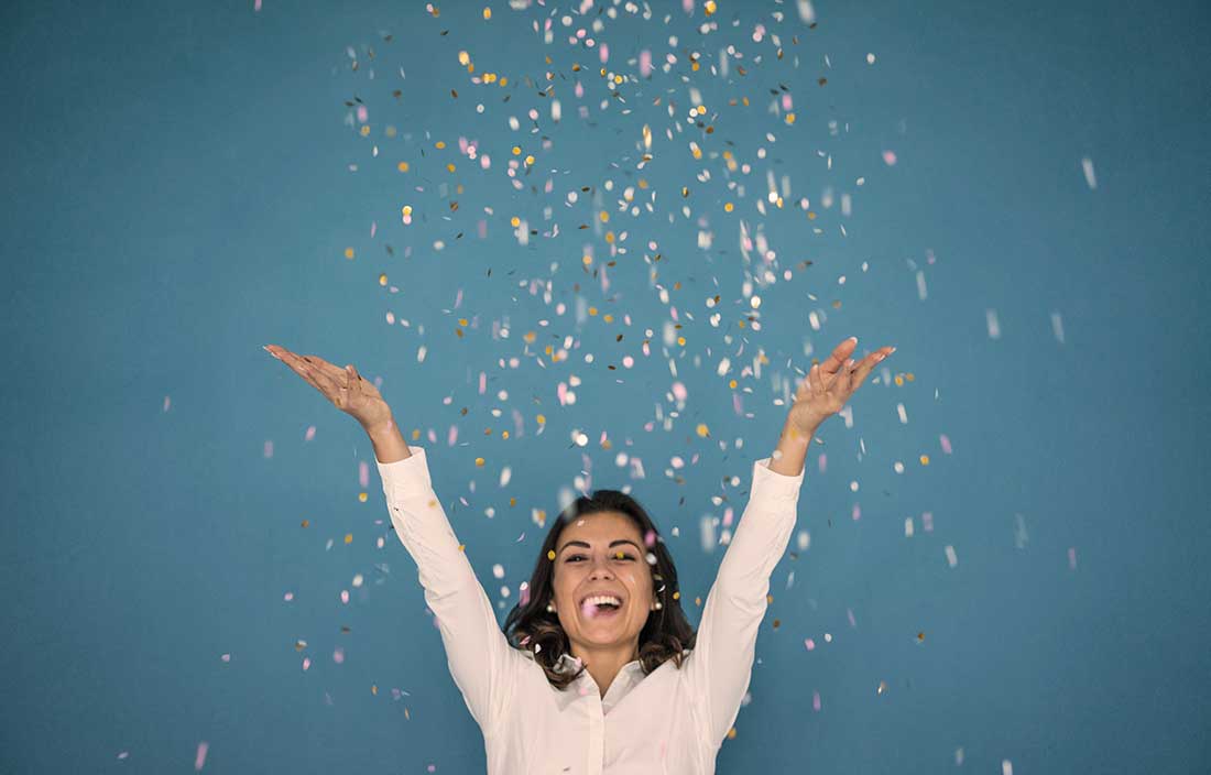 Office woman throwing confetti in the air on a blue background to celebrate award