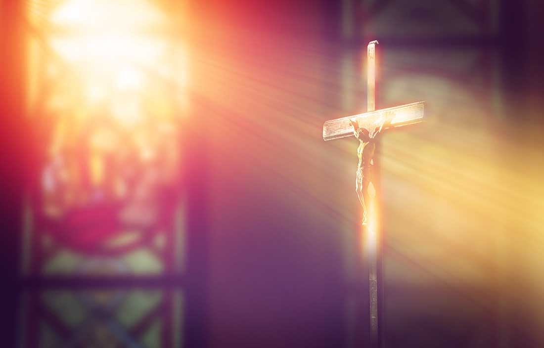 Light shining through stained glass on a crucifix in a church
