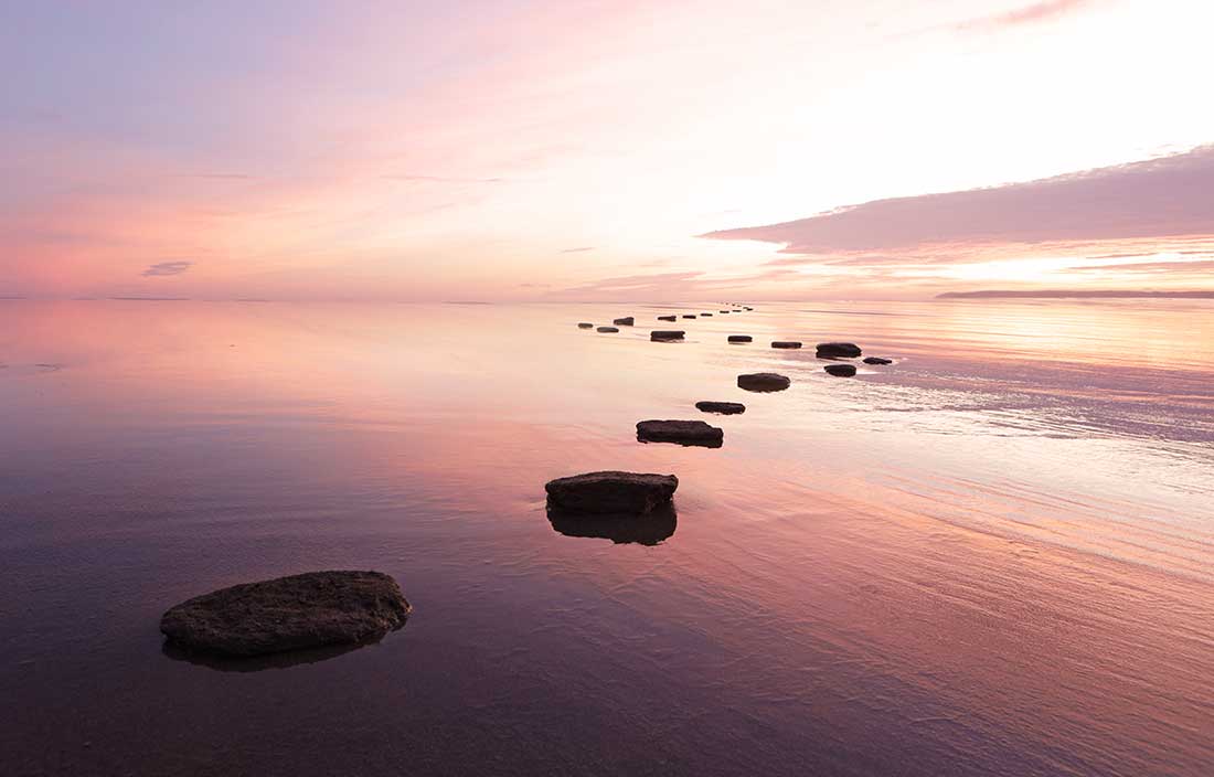 Stepping stones in water leading out into the horizon