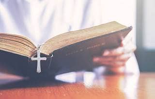 Close up of a person reading a bible at a table