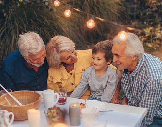 Grandparents gathered around and smiling at their grandchild.