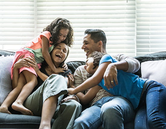 Family laughing and playing on a couch together. 