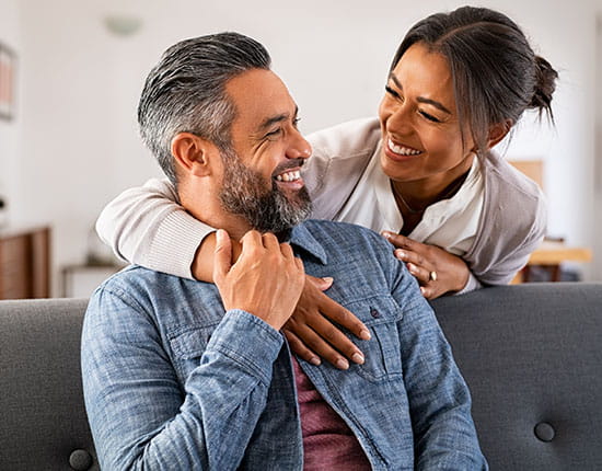 A couple sitting on a couch smiling.