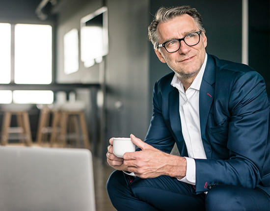 Business professional wearing a suit and holding a cup of coffee.