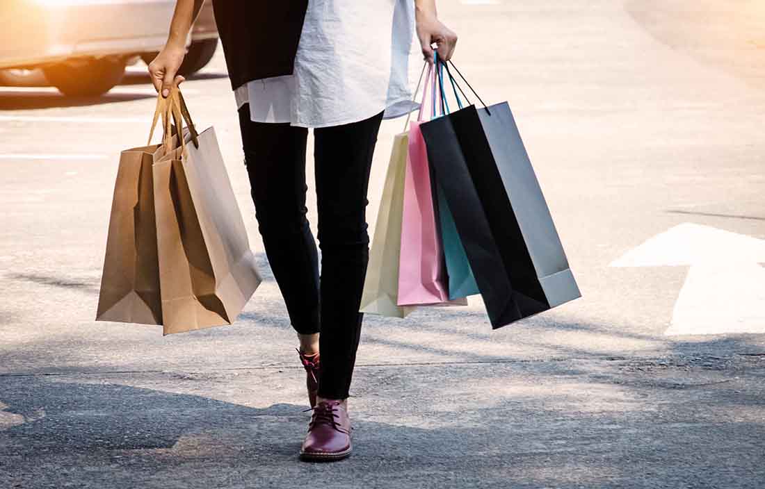 Person walking on sidewalk with shopping bags