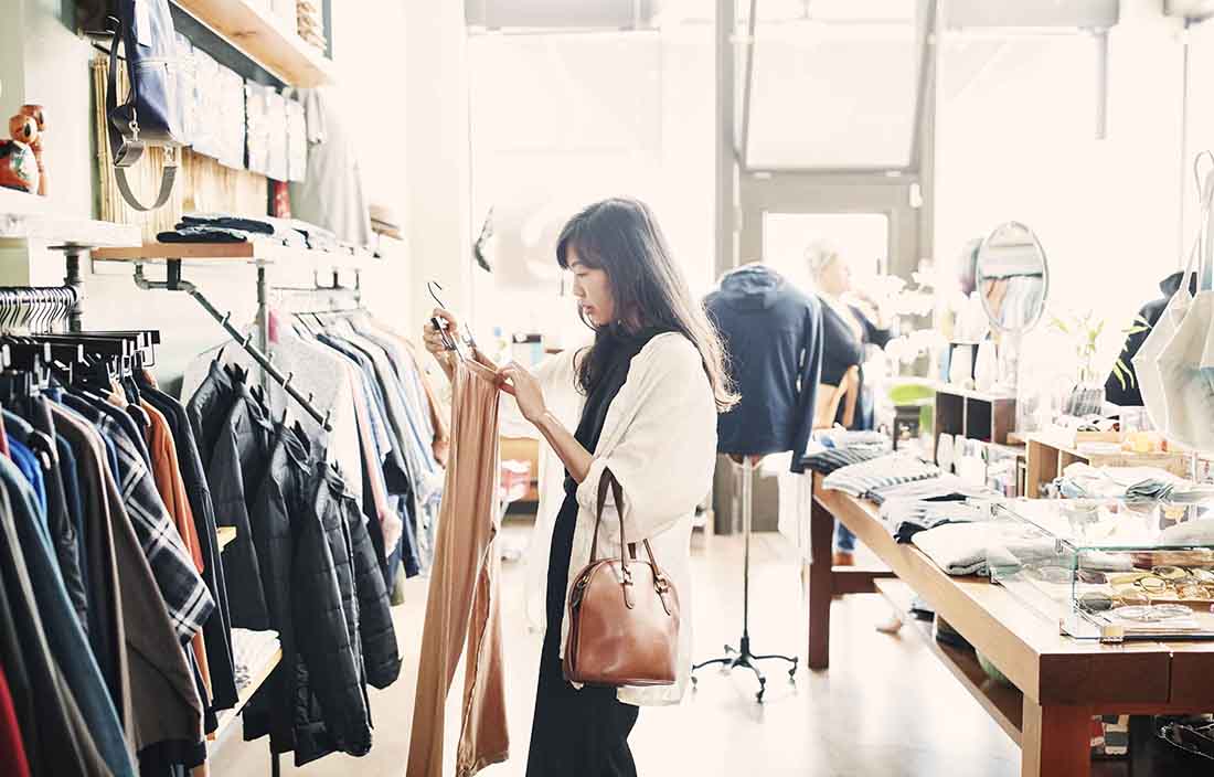 Woman standing looking at price on clothing piece