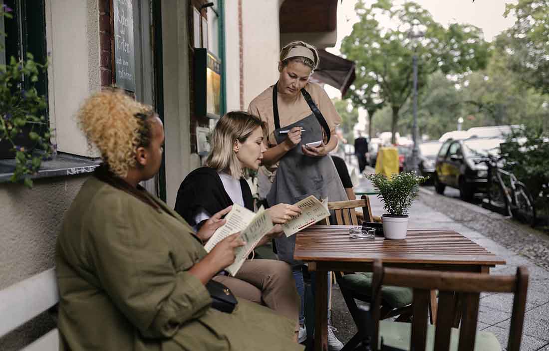 Two consumers order food at restaurant to waitress