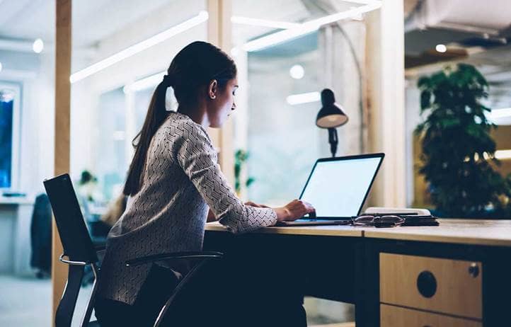 Woman sitting at a desk looking at a computer screen.