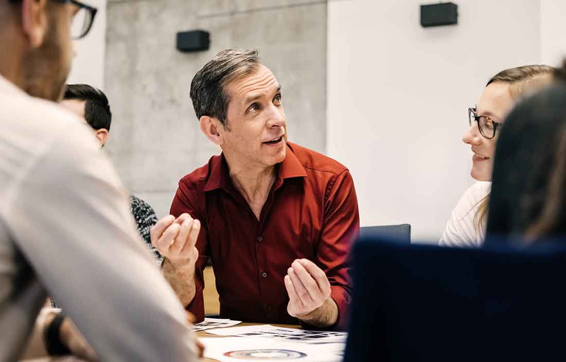 Man sitting at conference table with people talking