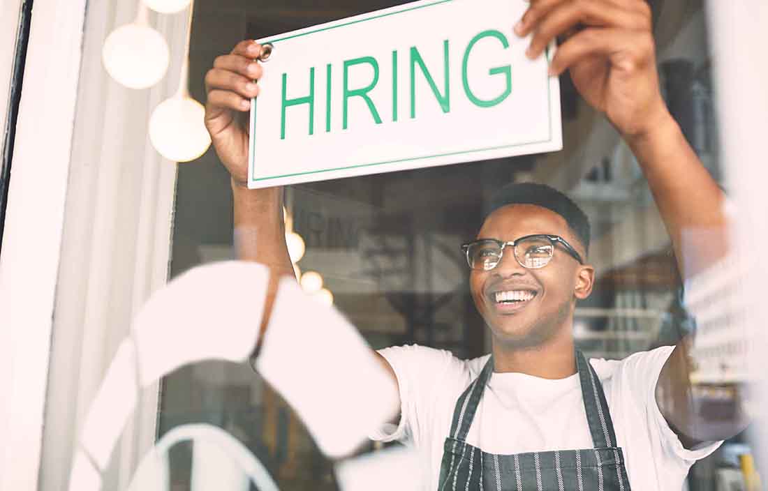 Man holding sign saying hiring due to increased jobs added to payrolls