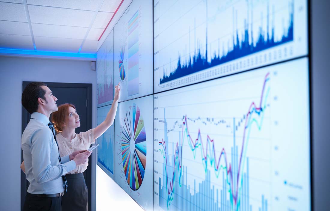 Two people looking at screens with GDP data
