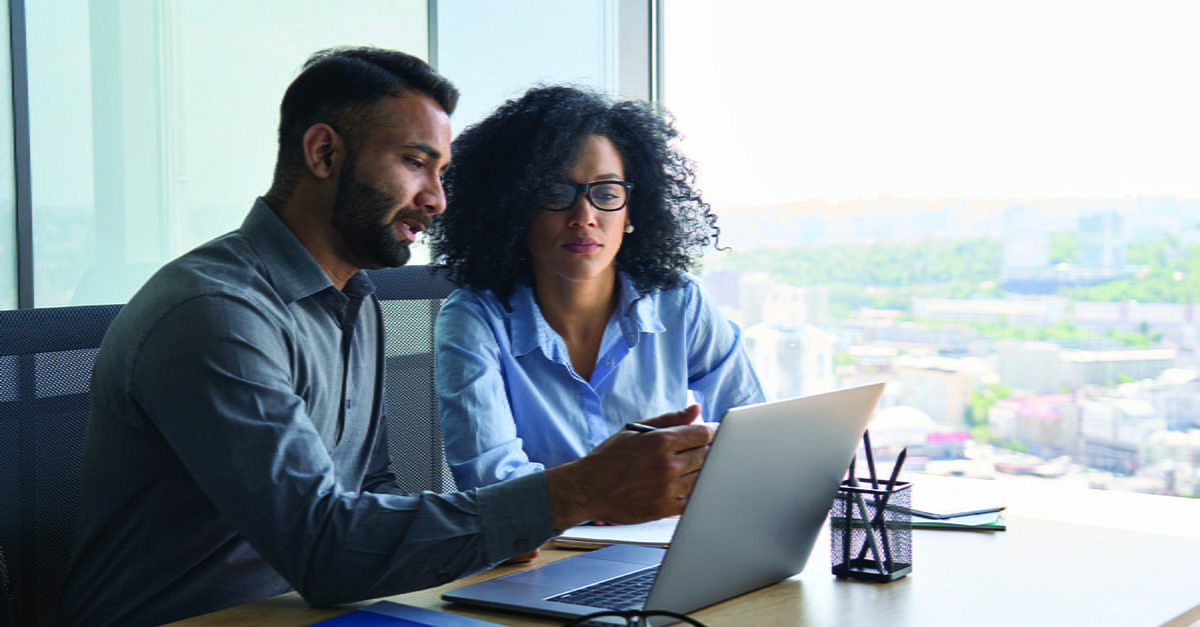 Two people sitting at a desk look at Gross Domestic Product data on the computer