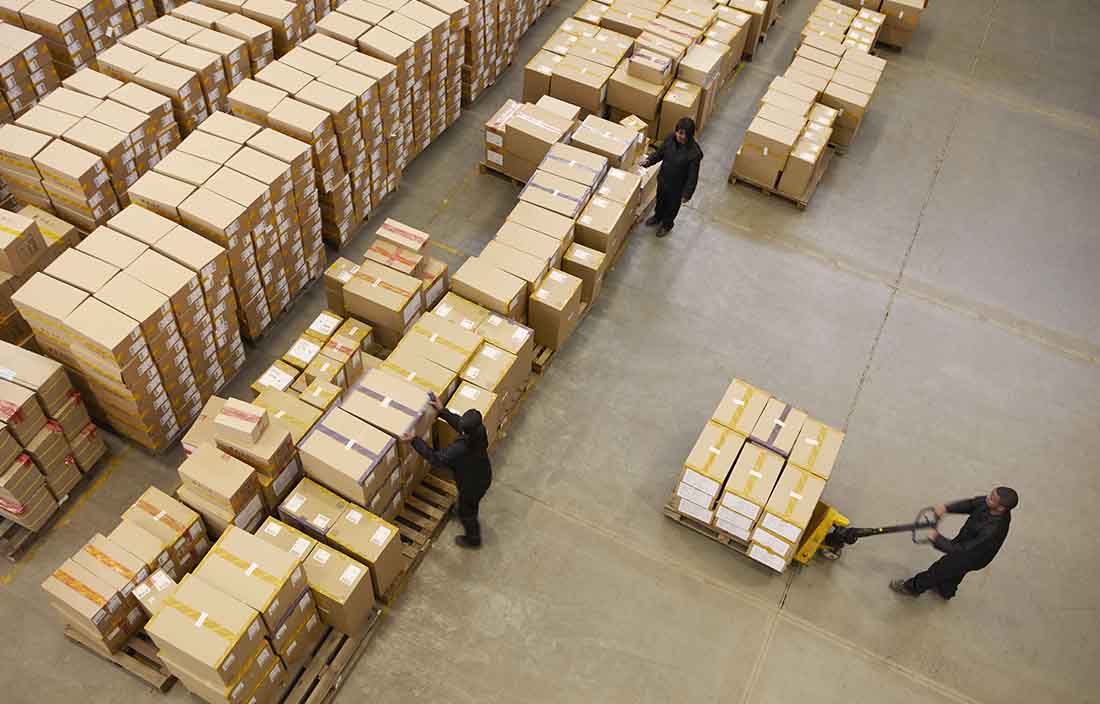 Boxes on a warehouse floor with people moving them