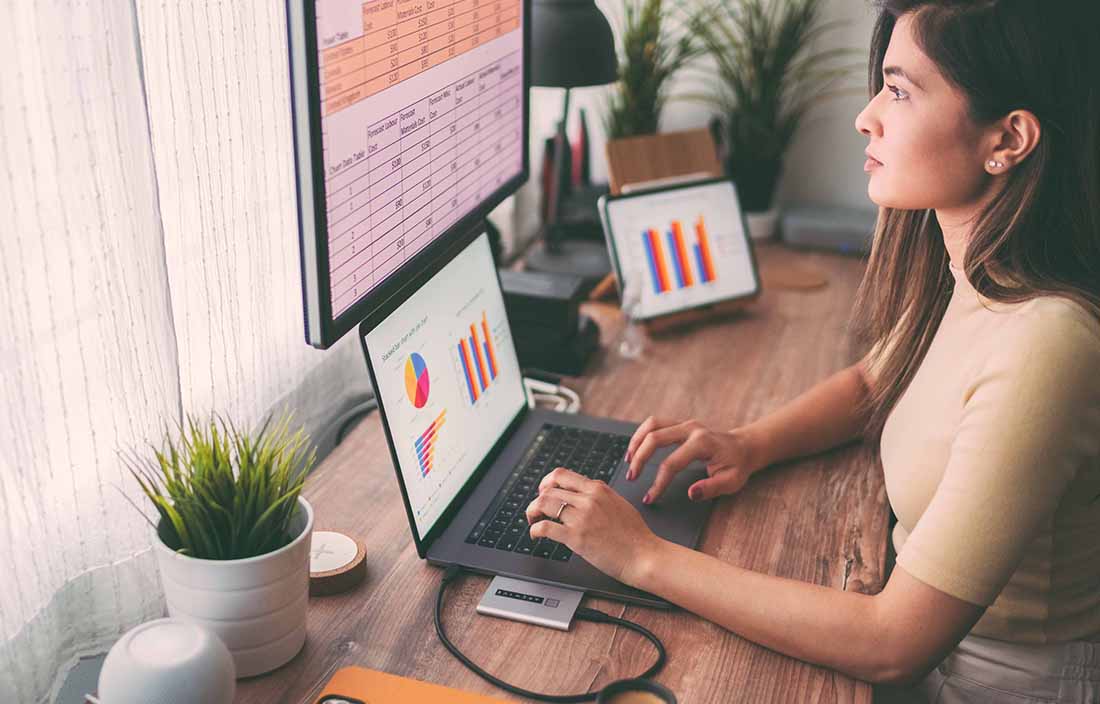 Woman sitting at desk looking at S&P 500 data on multiple screens