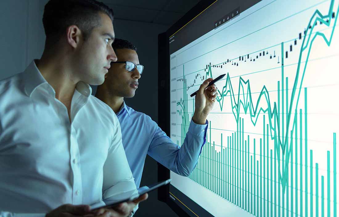 Two men looking at a chart of equity data on a board