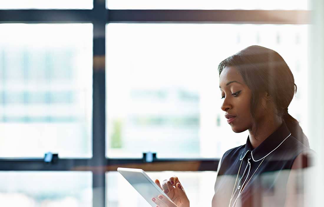 Woman looking down at a tablet in an office.