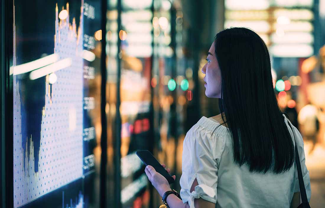 Woman standing at screen looking at chart