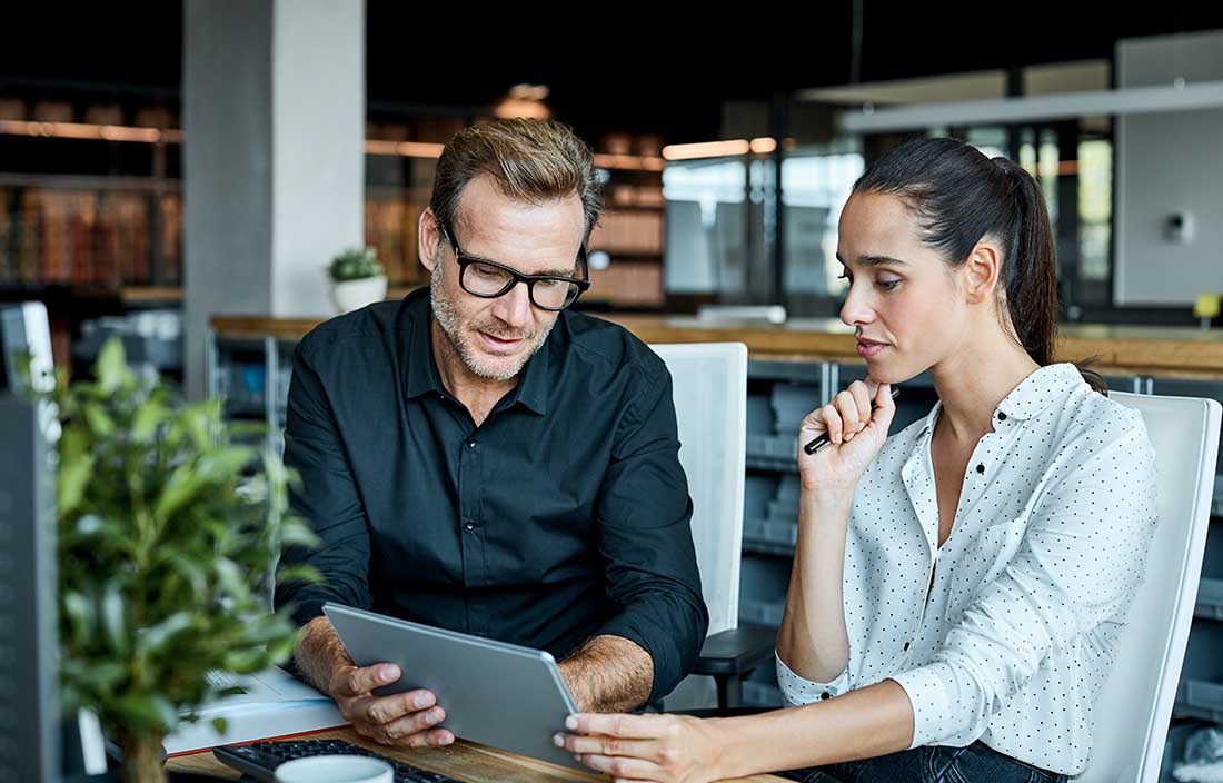 Two people looking at job creation data on a tablet