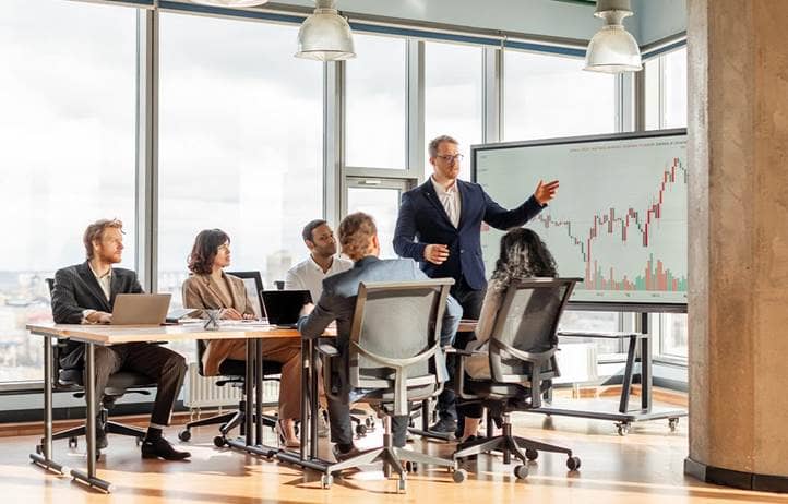 Group of people in an office looking at a chart on a screen.
