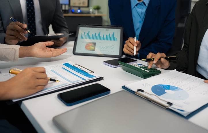 People looking at charts and graphs on paper and a tablet.