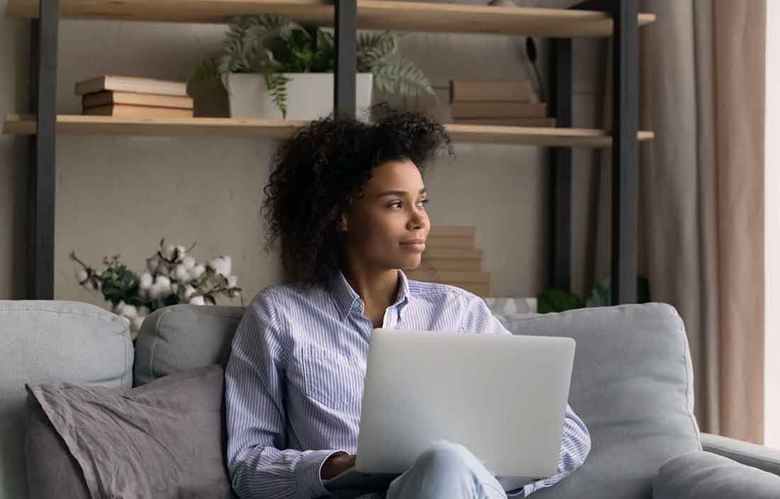 women working on laptop looking out window